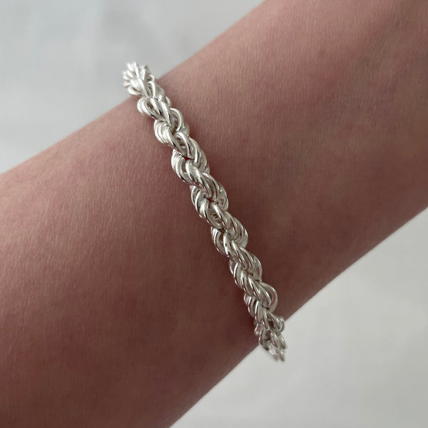 Silver braided bracelet on a wrist against a white background