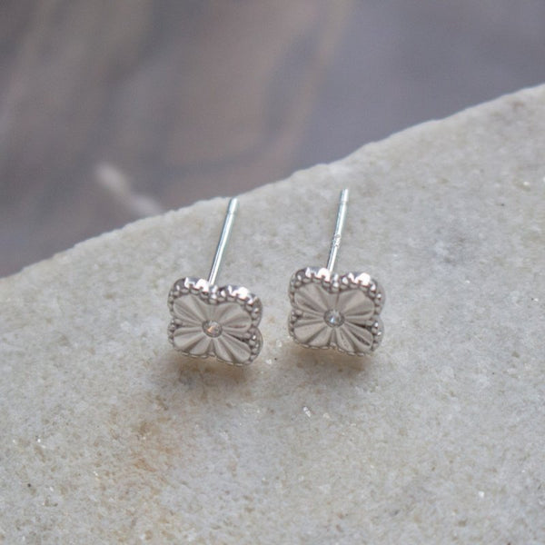 Silver clover earrings on a stone surface