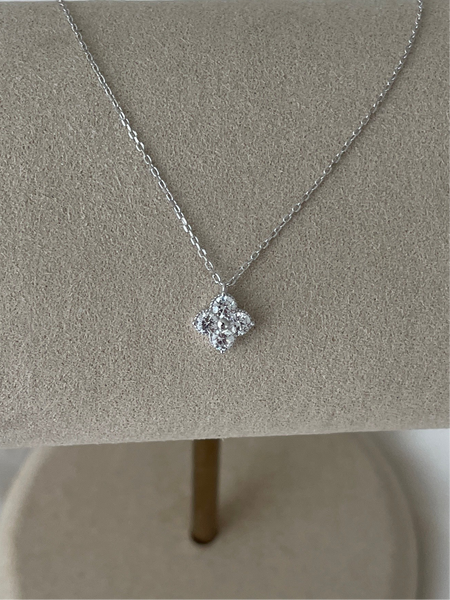 Silver necklace with a floral pendant on a gray stand