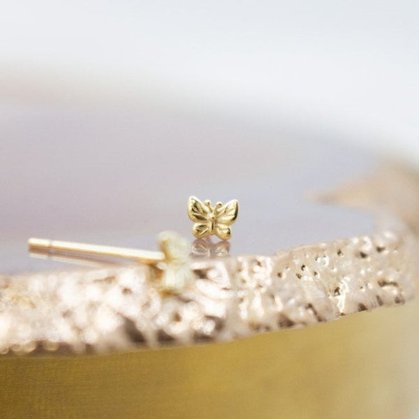 Gold butterfly earring on a blurred background