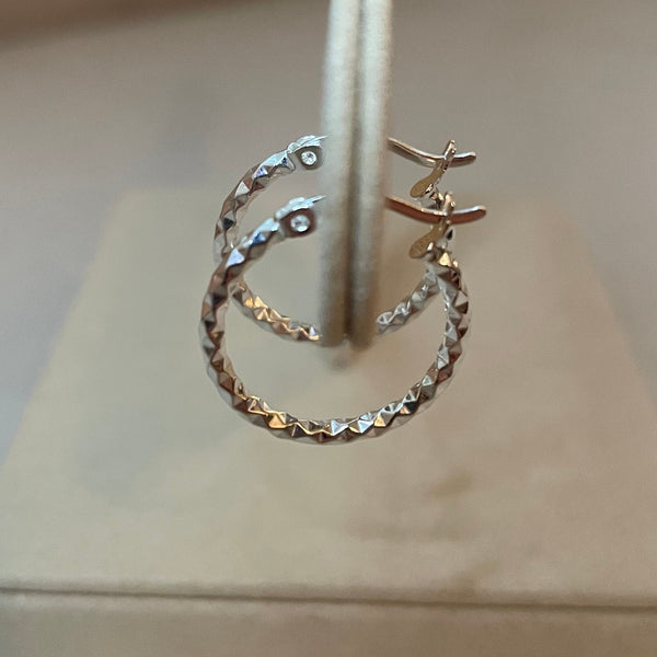 Pair of silver hoop earrings on a white stand against a neutral background