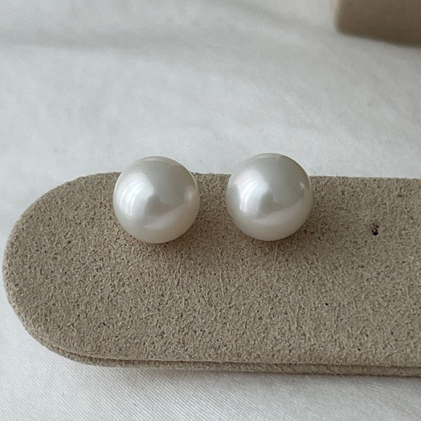 Pearl earrings on a gray stand with a white background