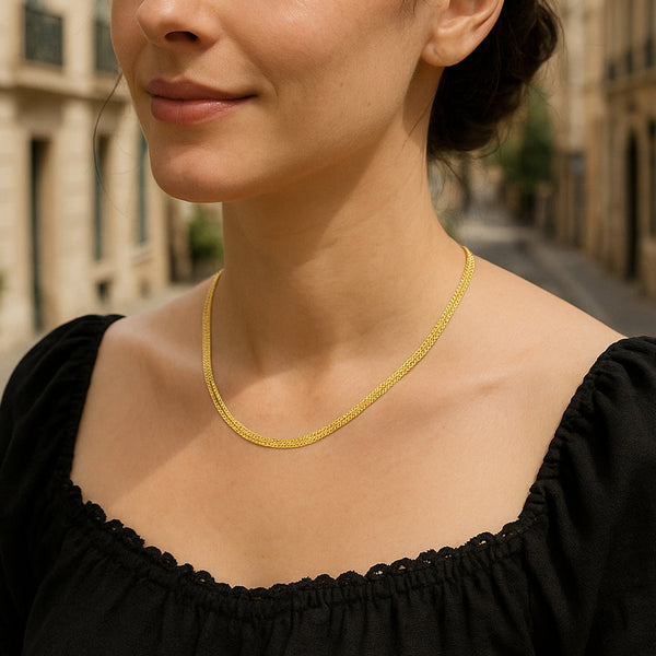Woman wearing a gold necklace with a blurred street background