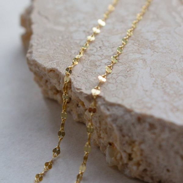 Gold necklace on a textured stone surface