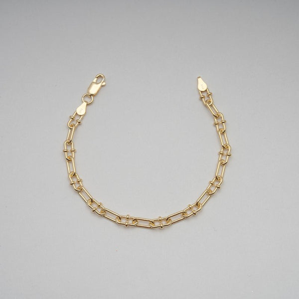 Gold chain bracelet on a gray background