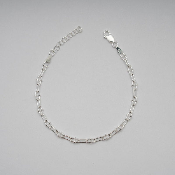 Silver chain bracelet on a gray background