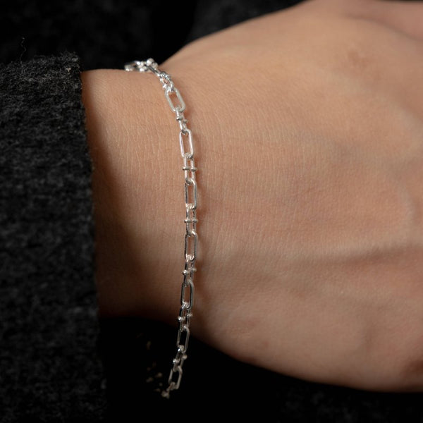 Silver bracelet on a wrist against a dark background