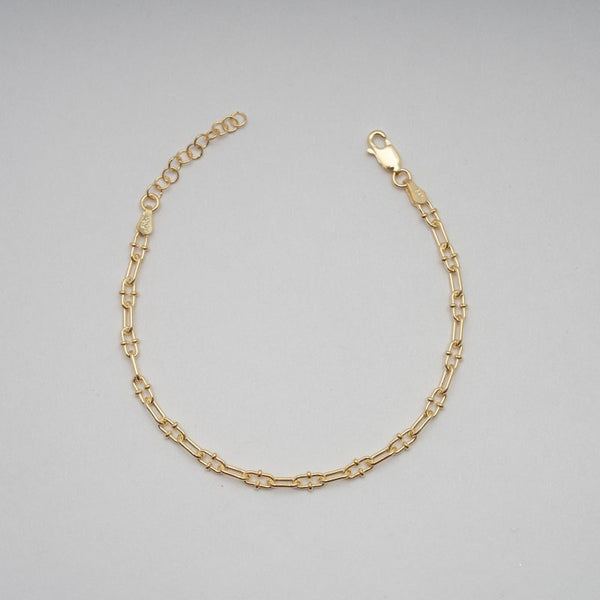 Gold chain bracelet on a gray background