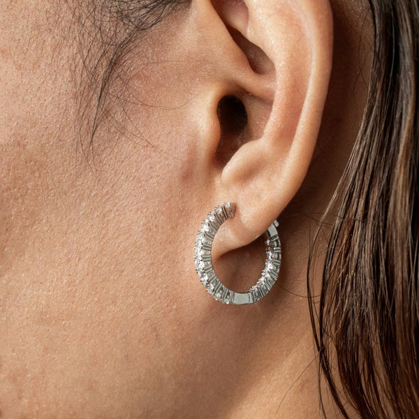Silver diamond hoop earring worn by a person