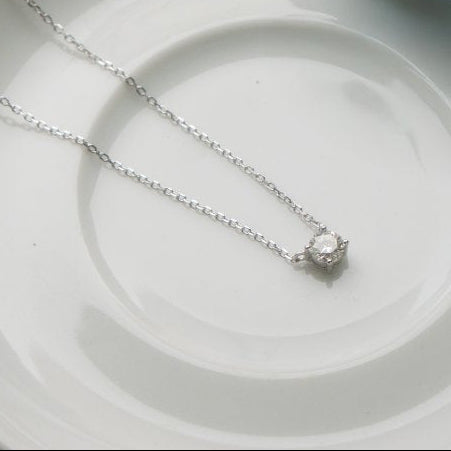Silver necklace with a diamond solitaire pendant on a white plate