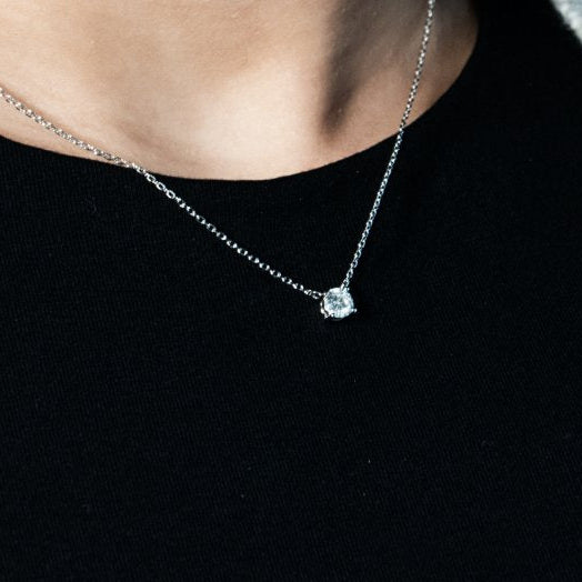 Necklace with a pendant worn by a person against a black background