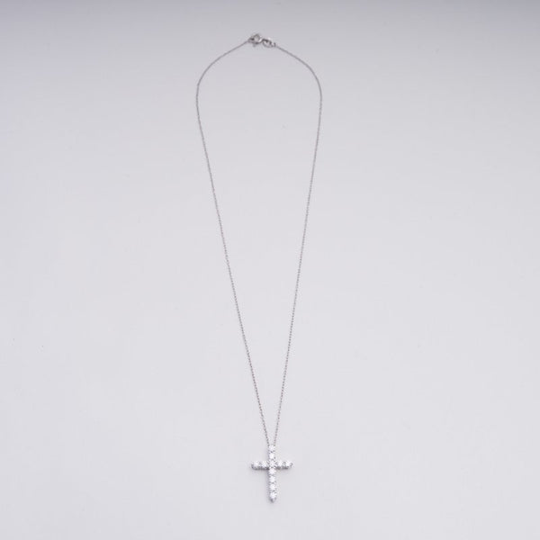 Silver cross necklace on a light gray background