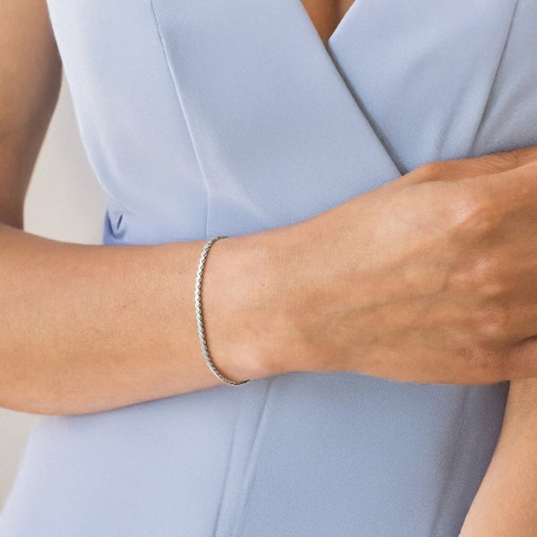 Person wearing a silver bracelet on a light blue background