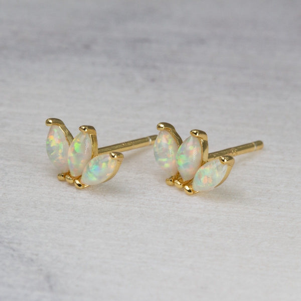 Gold earrings with opal stones on a light gray background