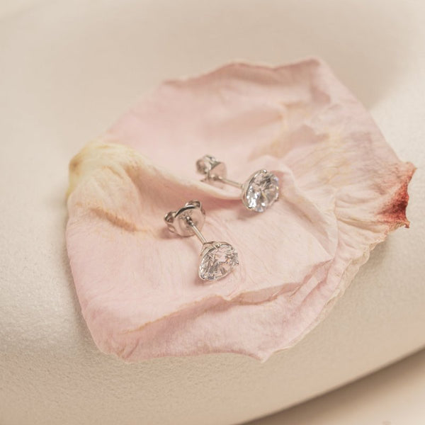 Pair of diamond earrings on a pink flower petal